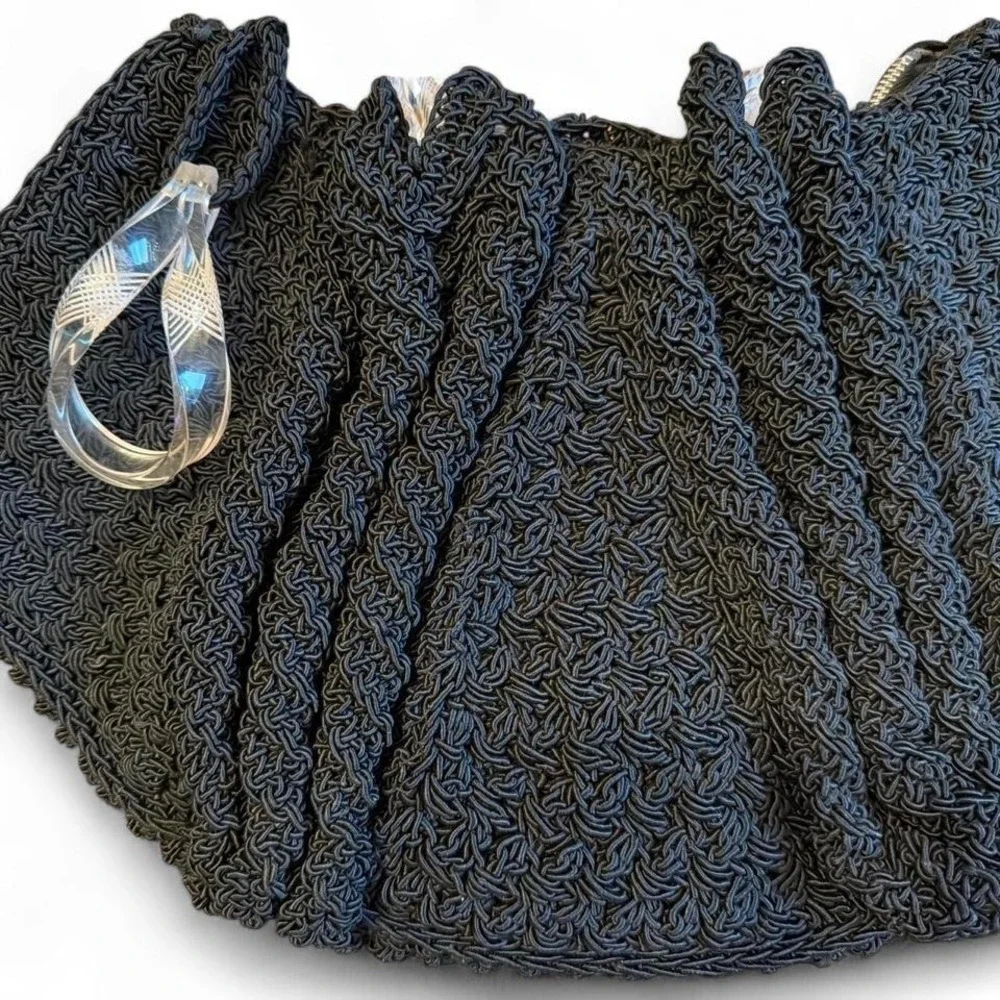 Black crocheted corde handbag featuring a clear, twisted Lucite handle